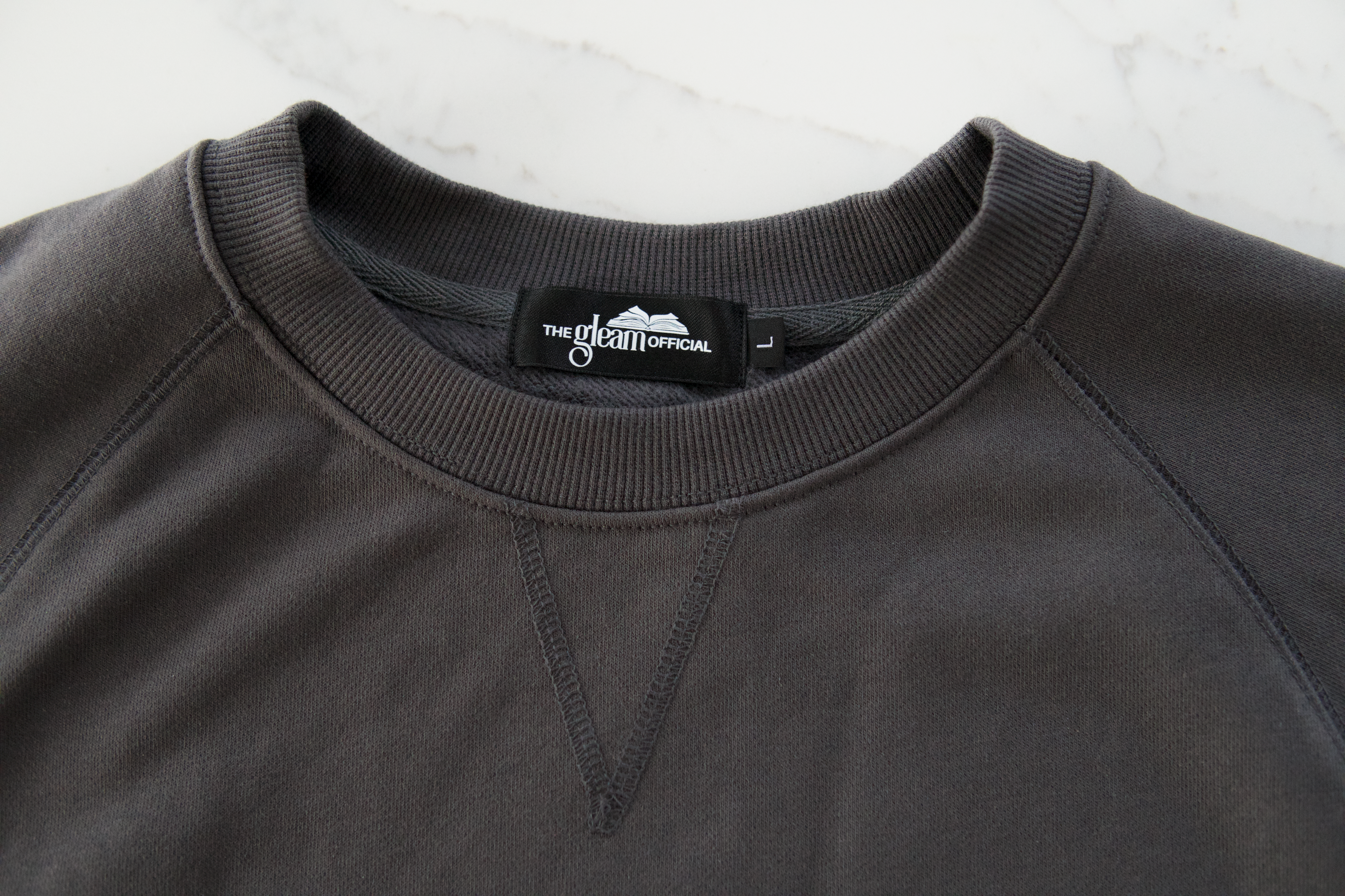 Close-up of thick cotton blend fabric and neckline detail on boxy dolman sleeve sweatshirt