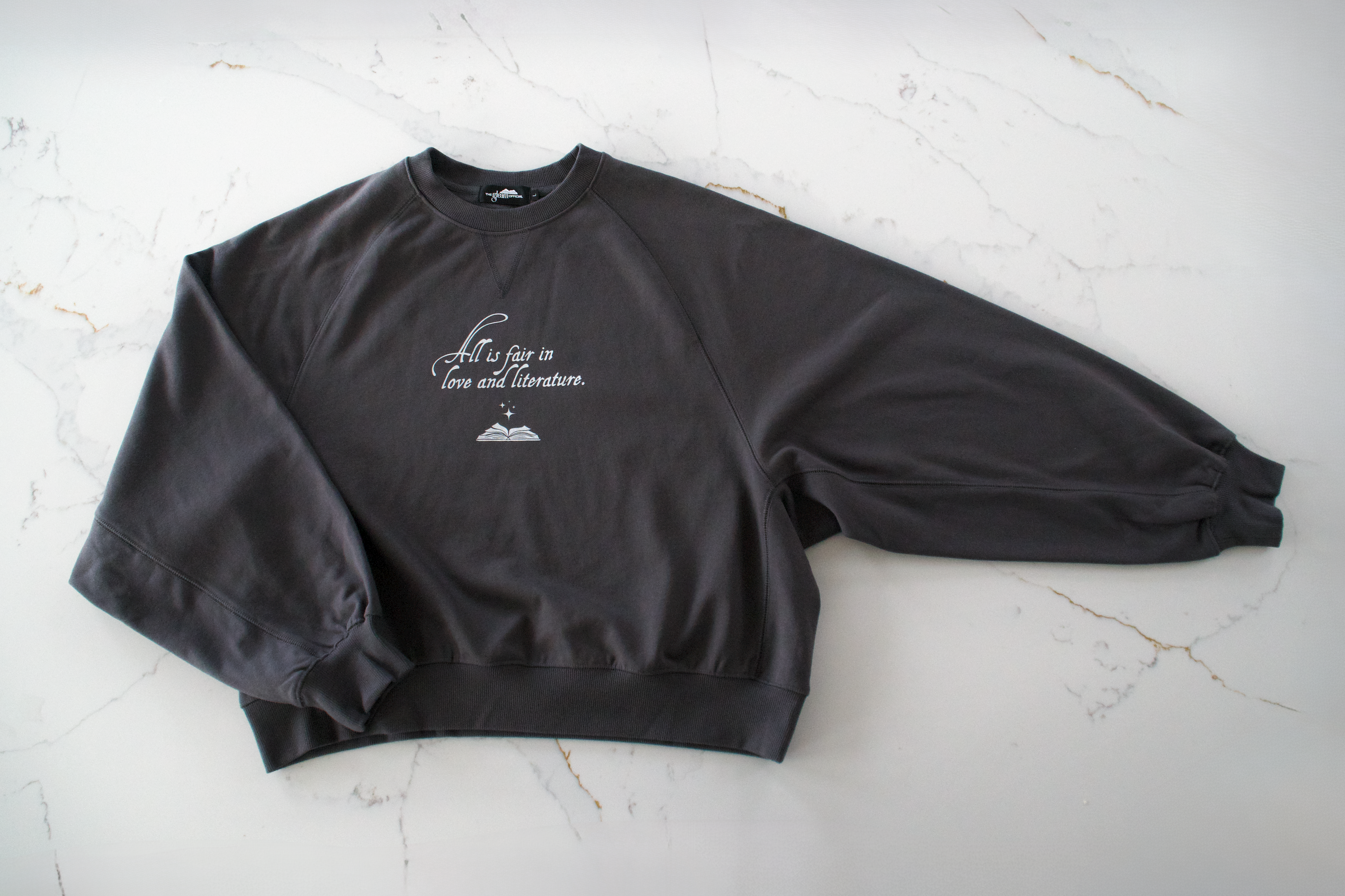 Dark gray heavyweight boxy sweatshirt with dolman sleeves styled in a minimal, bookish flat lay