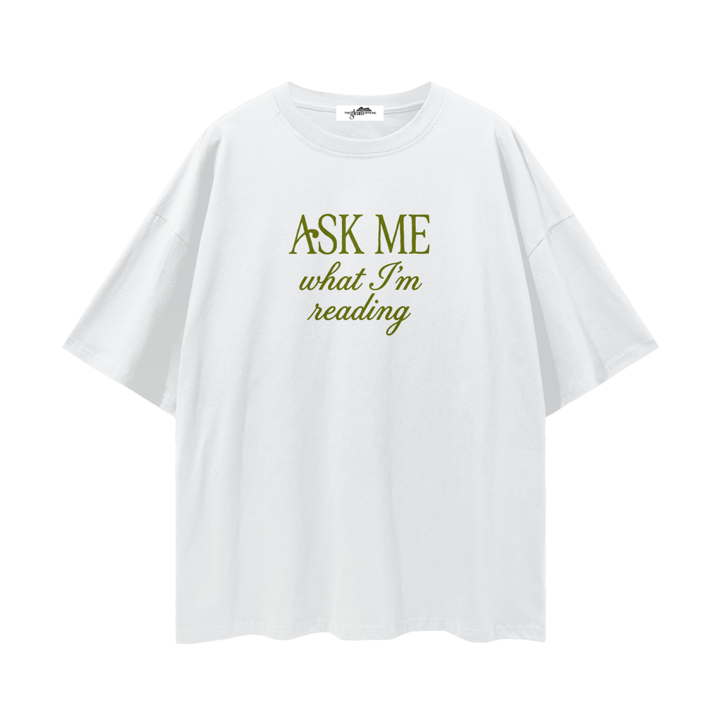 White t-shirt with green text 'Ask Me What I'm Reading' on a white background
