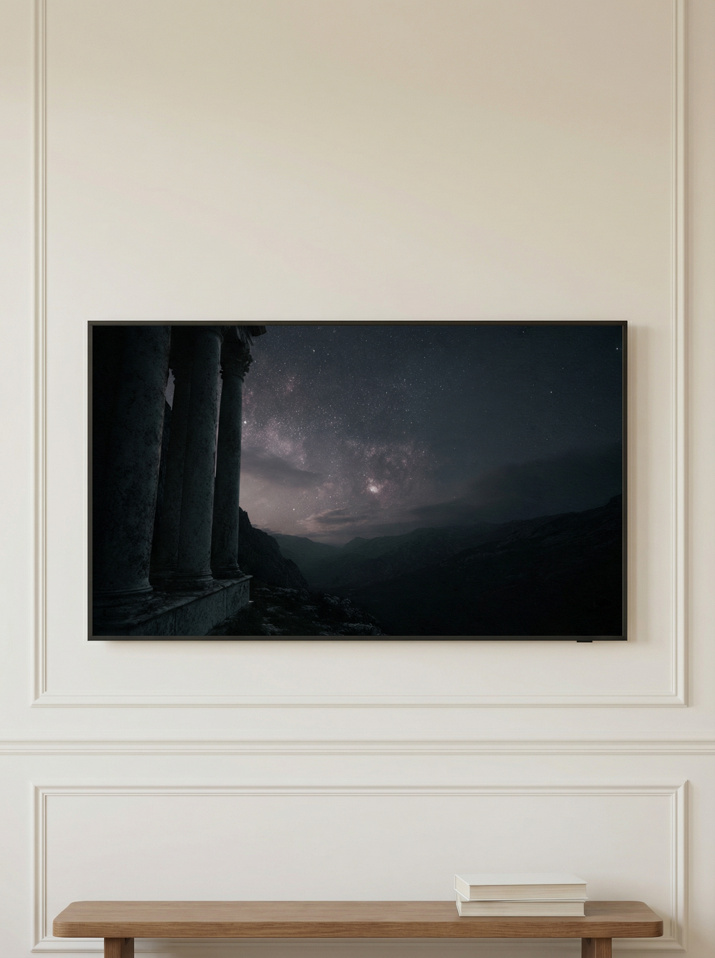 Frame TV artwork featuring a glowing night sky above jagged snowy peaks styled on a wooden console with books and a candle.