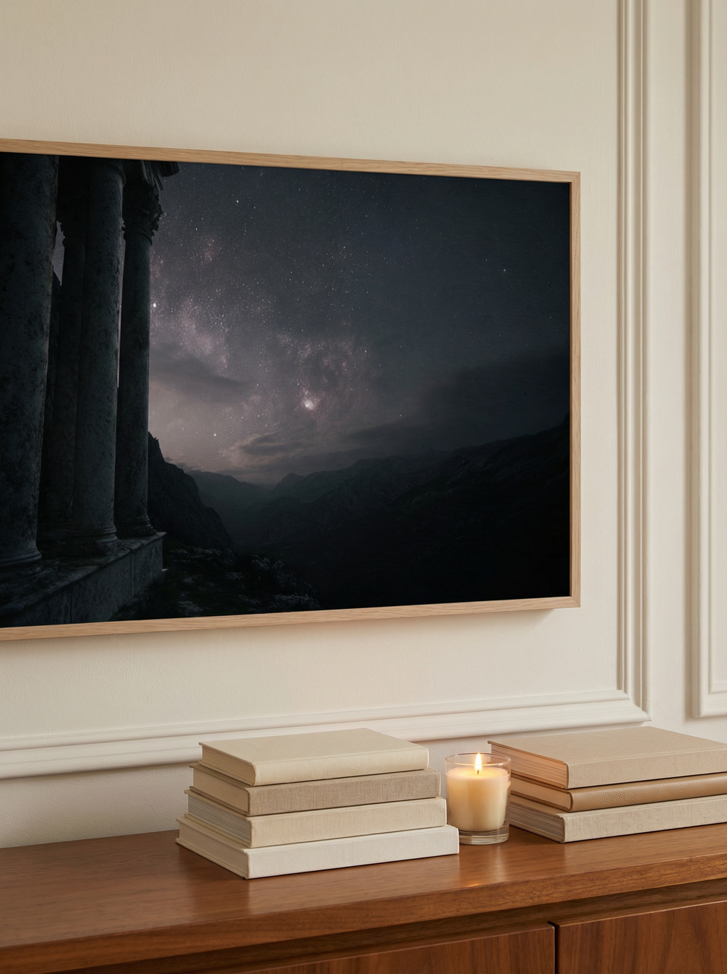 Side-angle close-up of a framed artwork showing ancient pillars framing a star-filled sky over distant mountains.